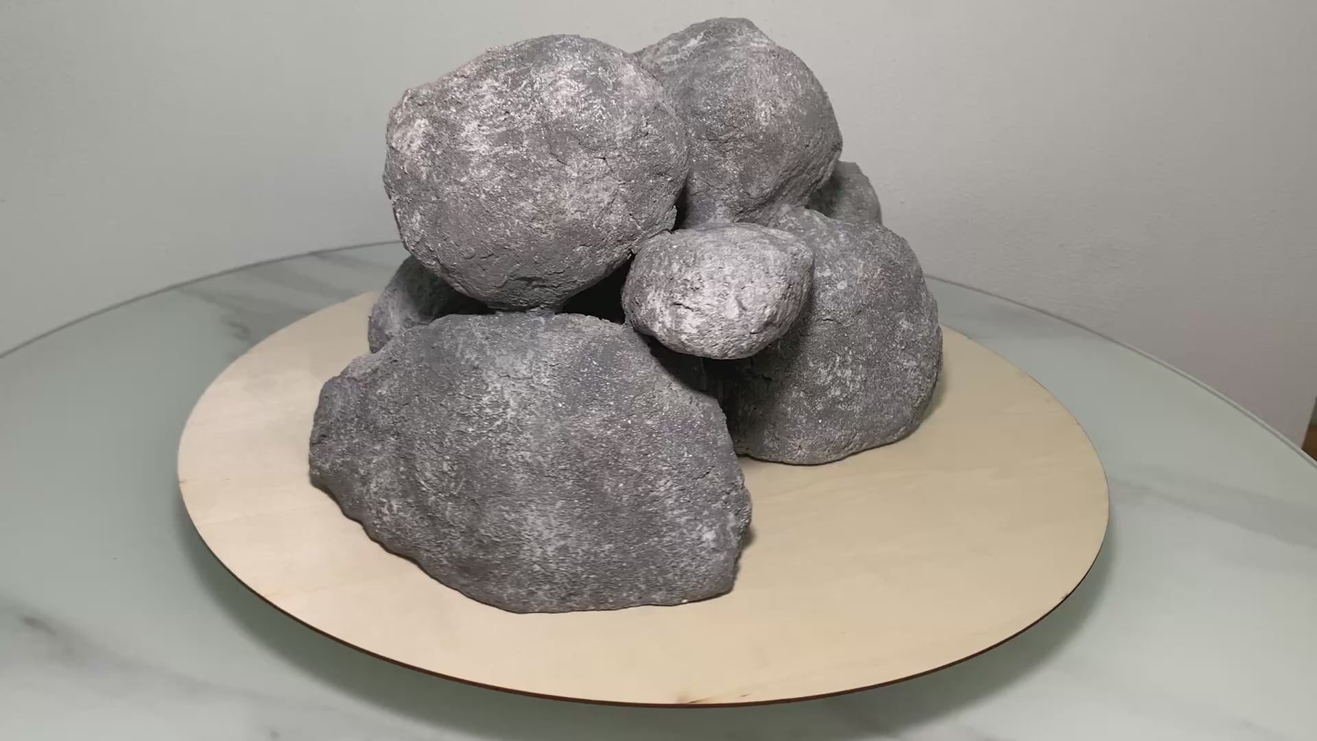 „Rotierendes Video einer grauen Aquarium-Höhlenformation aus drei verbundenen Felsen, präsentiert auf einem runden Tablett zur Ansicht der Höhleneingänge aus 360 Grad.“