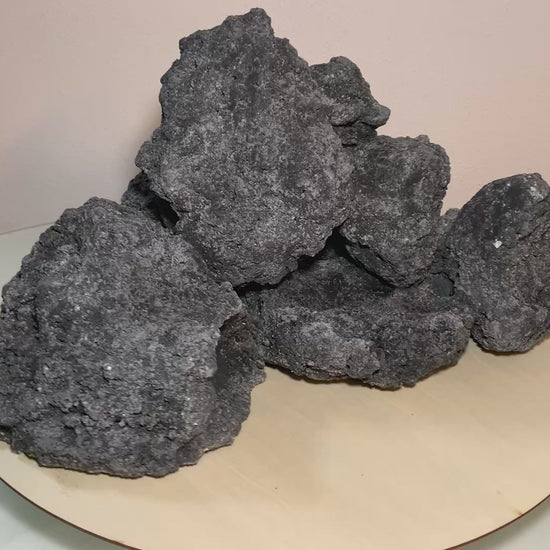 „Rotierendes Video einer schwarzen Aquarium-Höhlenformation aus drei verbundenen Felsen, präsentiert auf einem runden Tablett zur Ansicht der Höhleneingänge aus 360 Grad.“