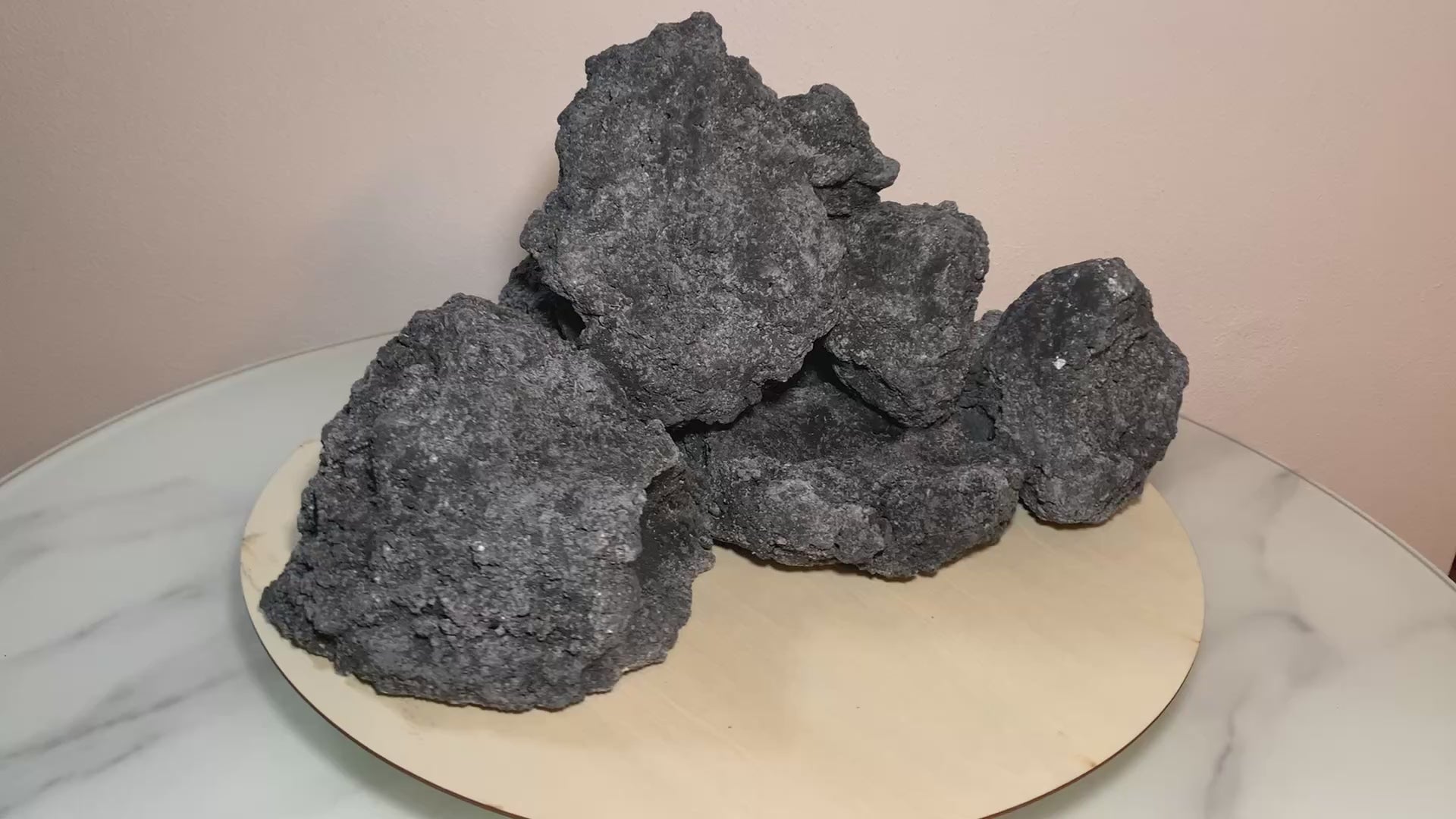 „Rotierendes Video einer schwarzen Aquarium-Höhlenformation aus drei verbundenen Felsen, präsentiert auf einem runden Tablett zur Ansicht der Höhleneingänge aus 360 Grad.“