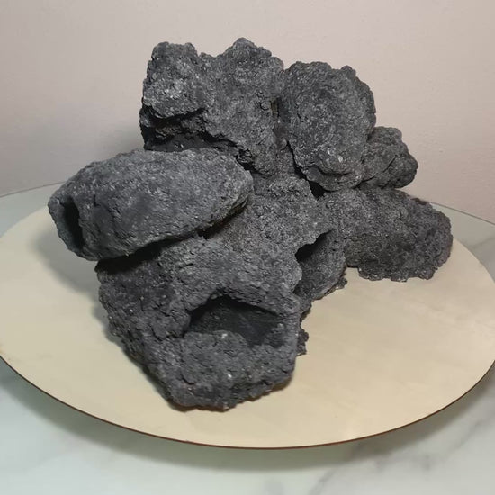 „Rotierendes Video einer schwarzenu Aquarium-Höhlenformation aus drei verbundenen Felsen, präsentiert auf einem runden Tablett zur Ansicht der Höhleneingänge aus 360 Grad.“