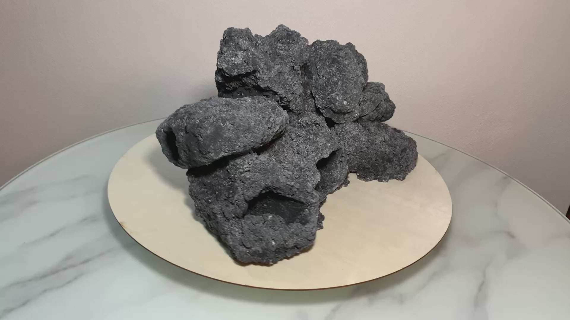 „Rotierendes Video einer schwarzenu Aquarium-Höhlenformation aus drei verbundenen Felsen, präsentiert auf einem runden Tablett zur Ansicht der Höhleneingänge aus 360 Grad.“